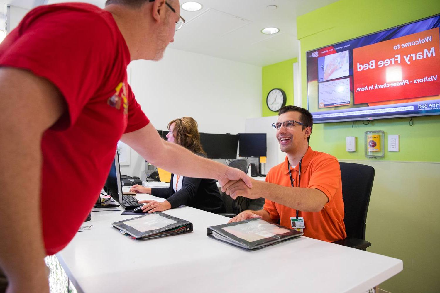 volunteer is seated at a check-in table and greets a guest